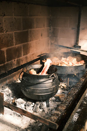 Homemade meat stock simmering gently in a rustic pot, with steam rising softly.