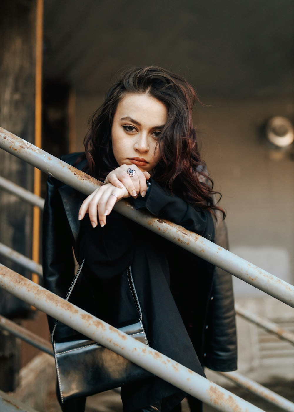 a woman in a black jacket leaning on a rail