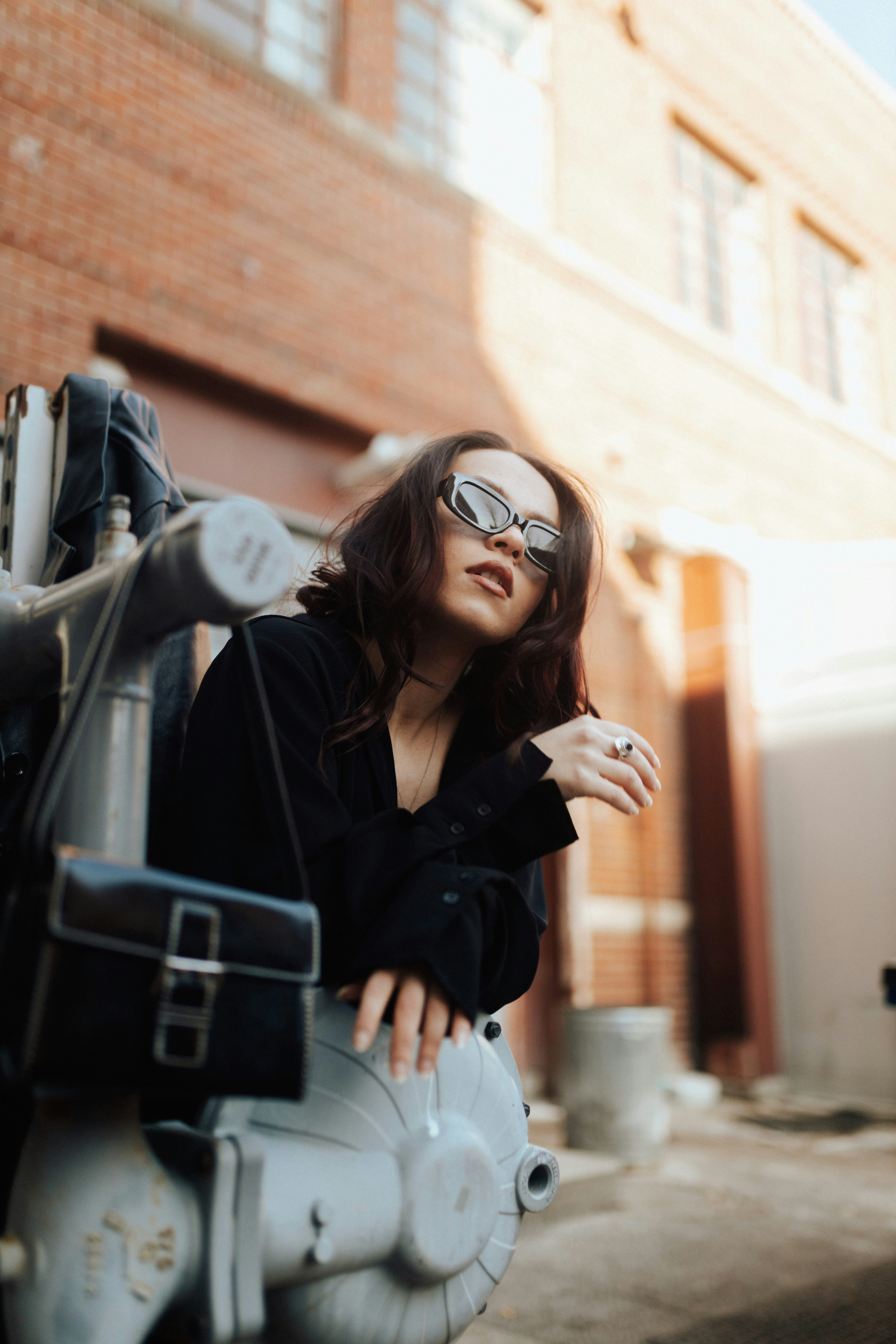 a woman wearing sunglasses leaning on a motorcycle
