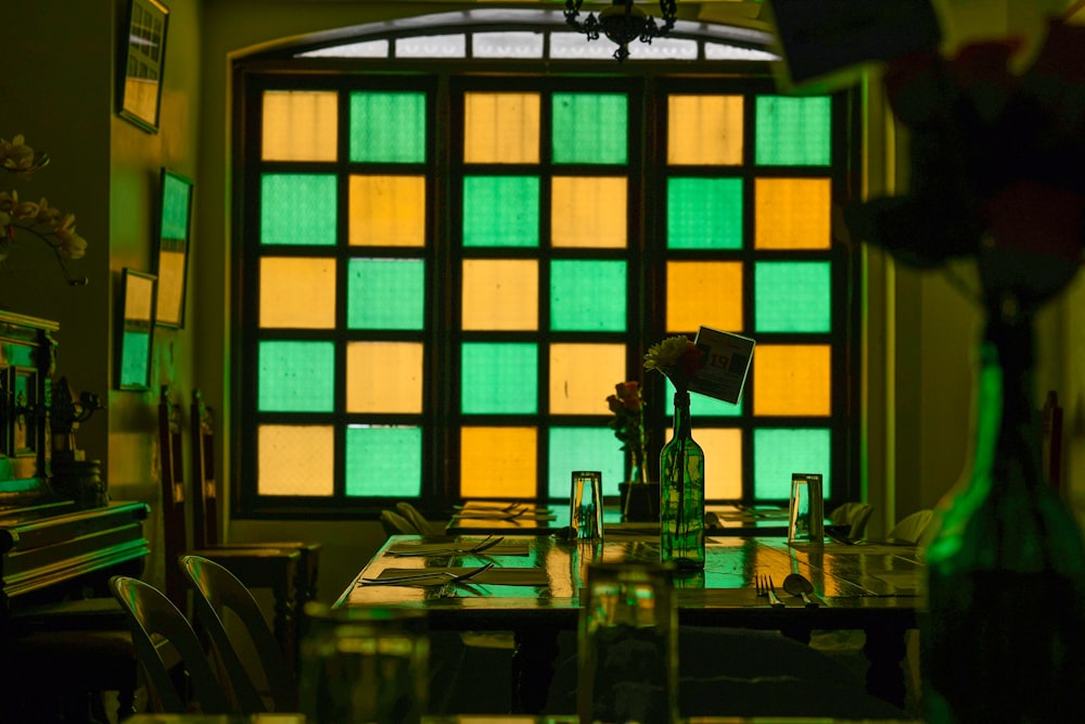 a dining room table with a vase of flowers in front of a stained glass window