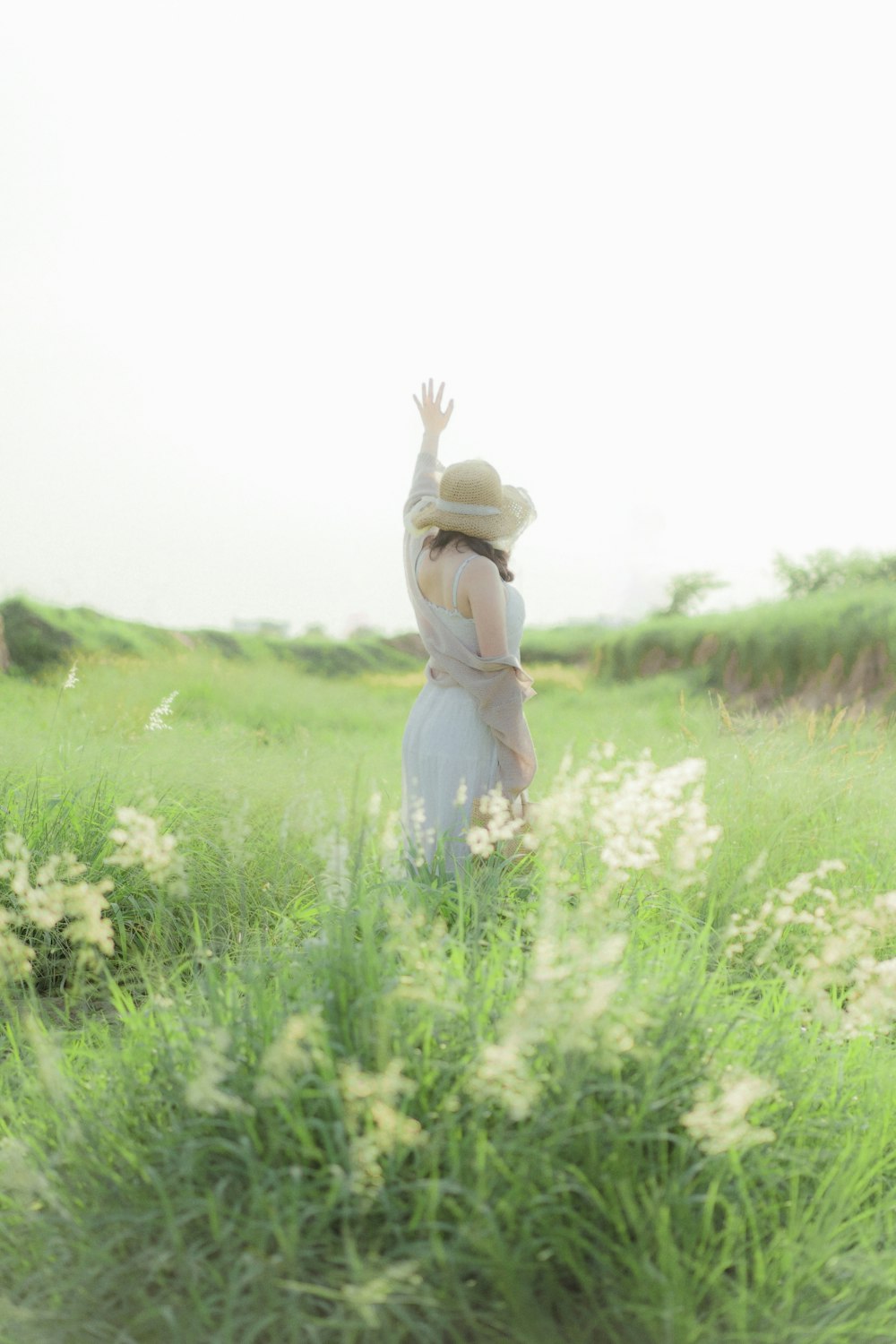 a woman in a white dress and hat in a field