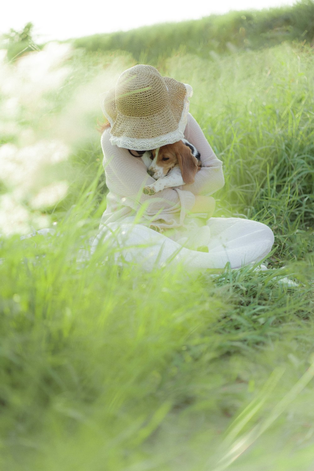 a woman sitting in the grass with her dog