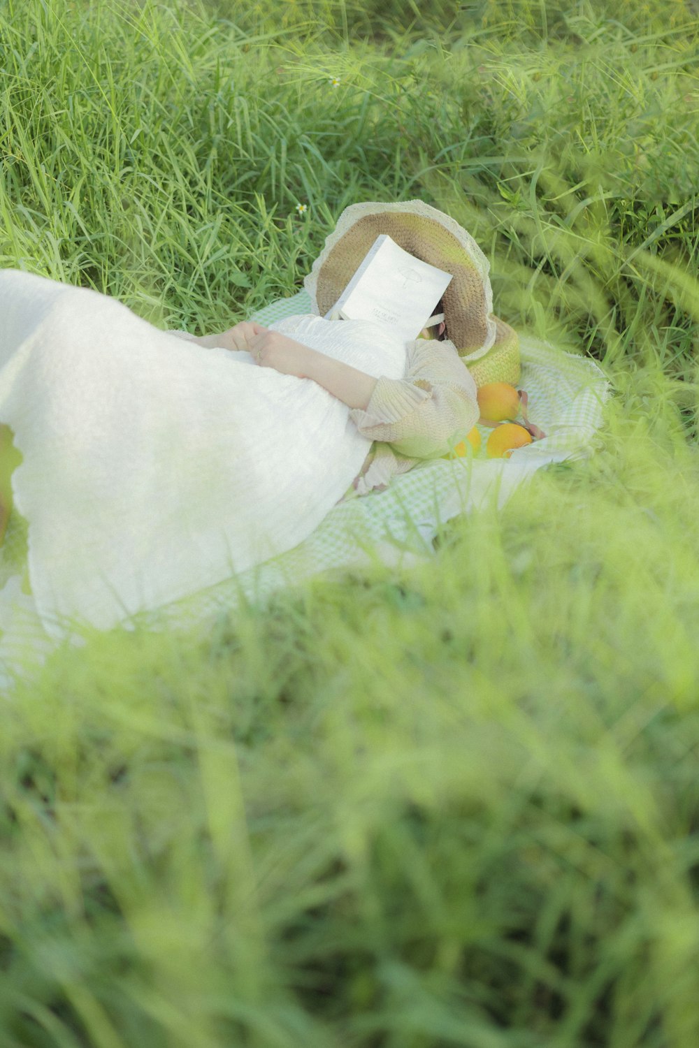 白いドレスを着た女性が草の中に横たわっている