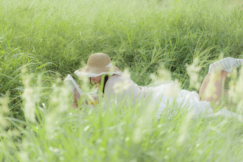 a woman laying in the grass reading a book