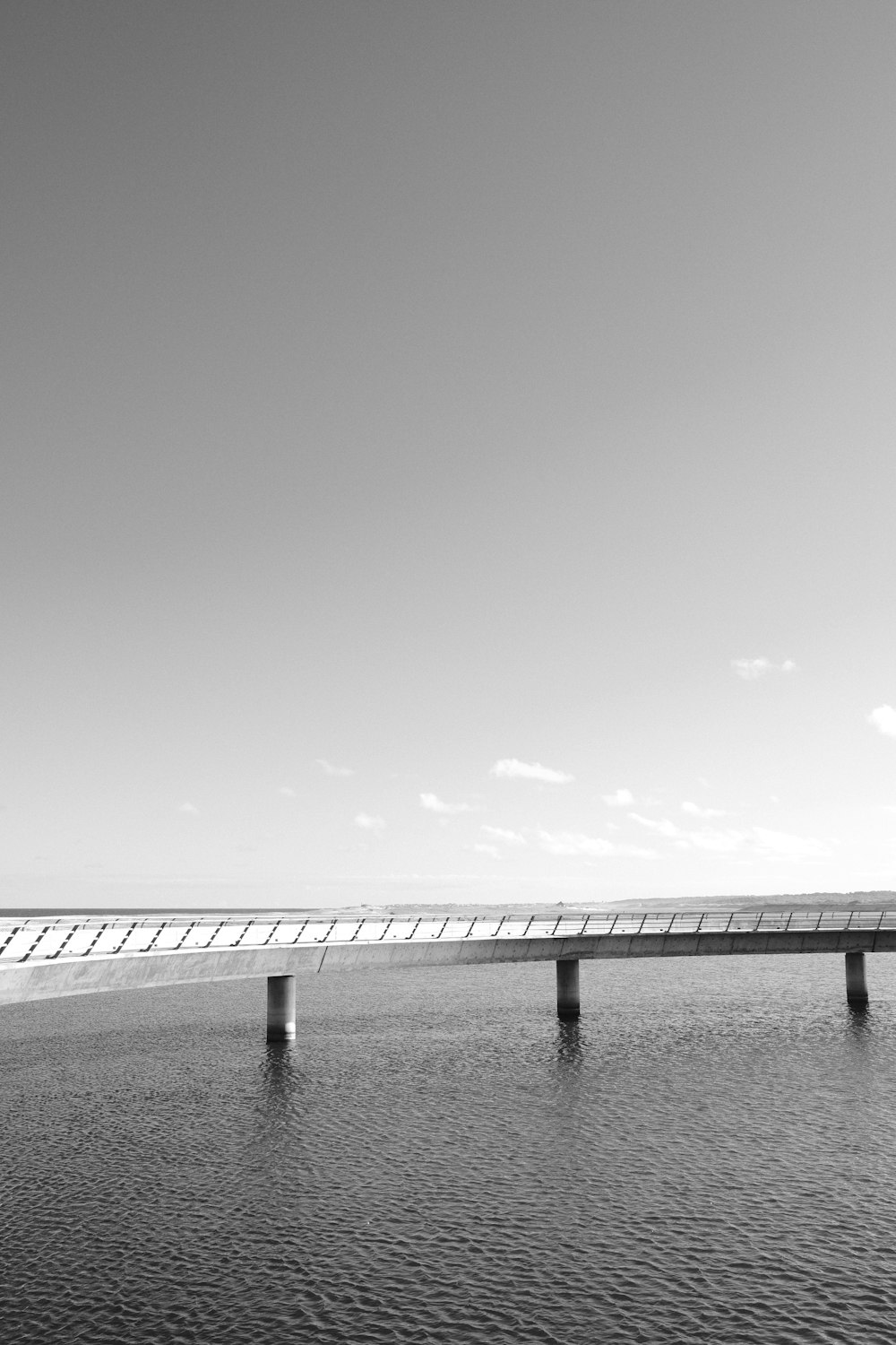 uma foto em preto e branco de uma ponte sobre a água