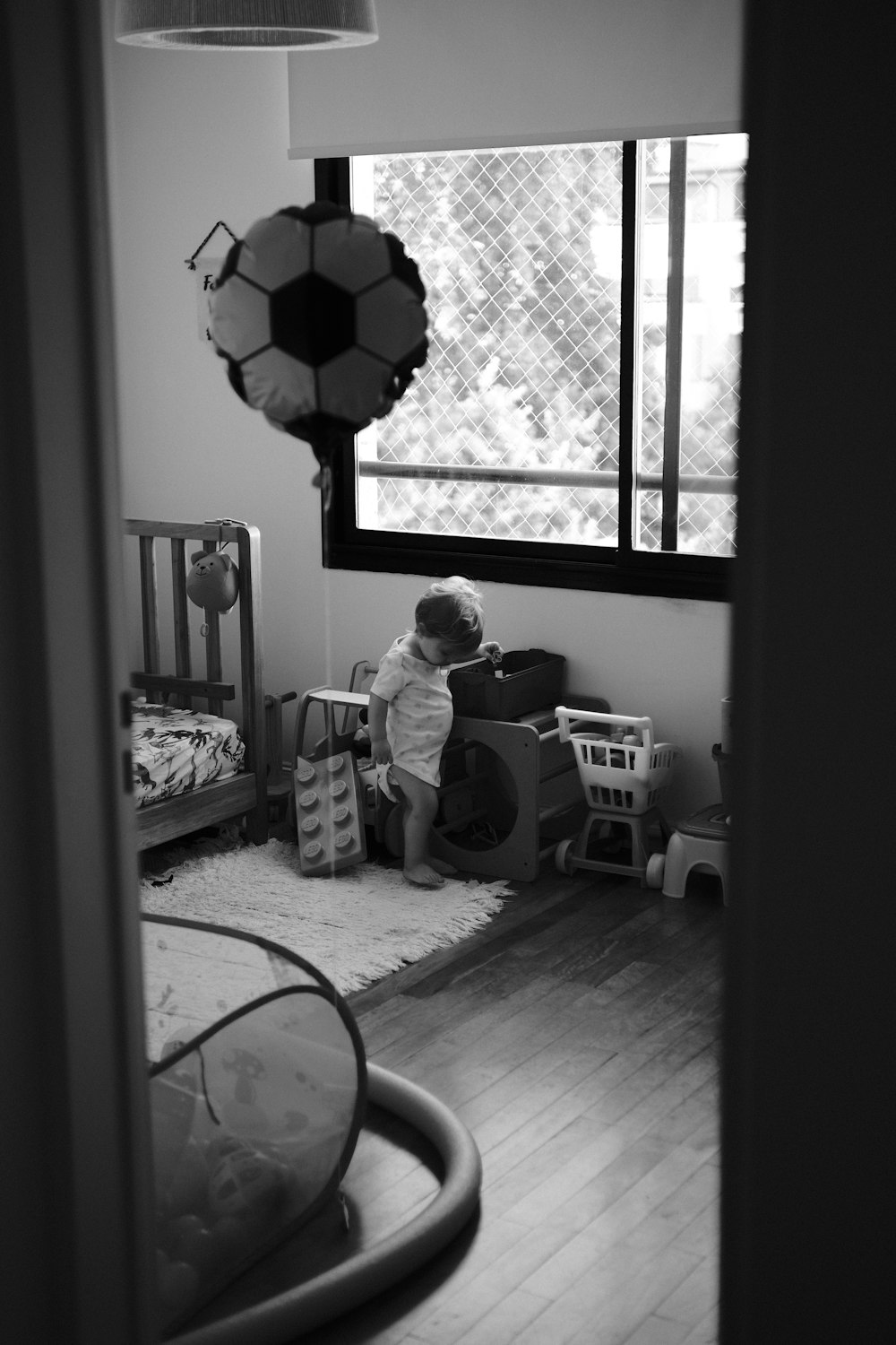 a small child sitting in a room with a crib