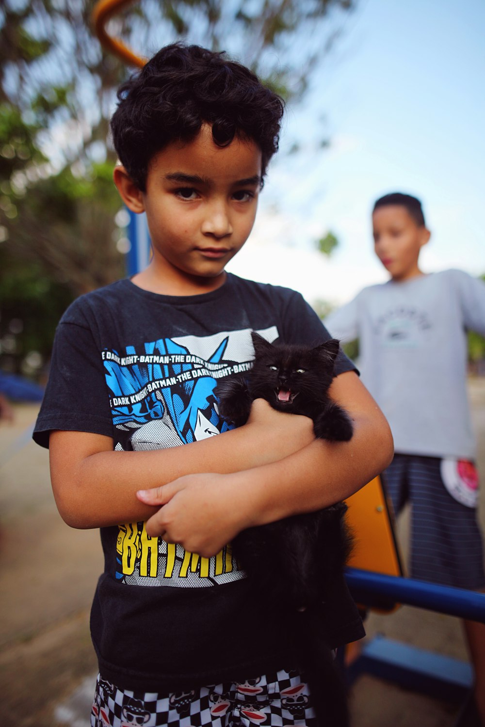 a young boy holding a black cat in his arms