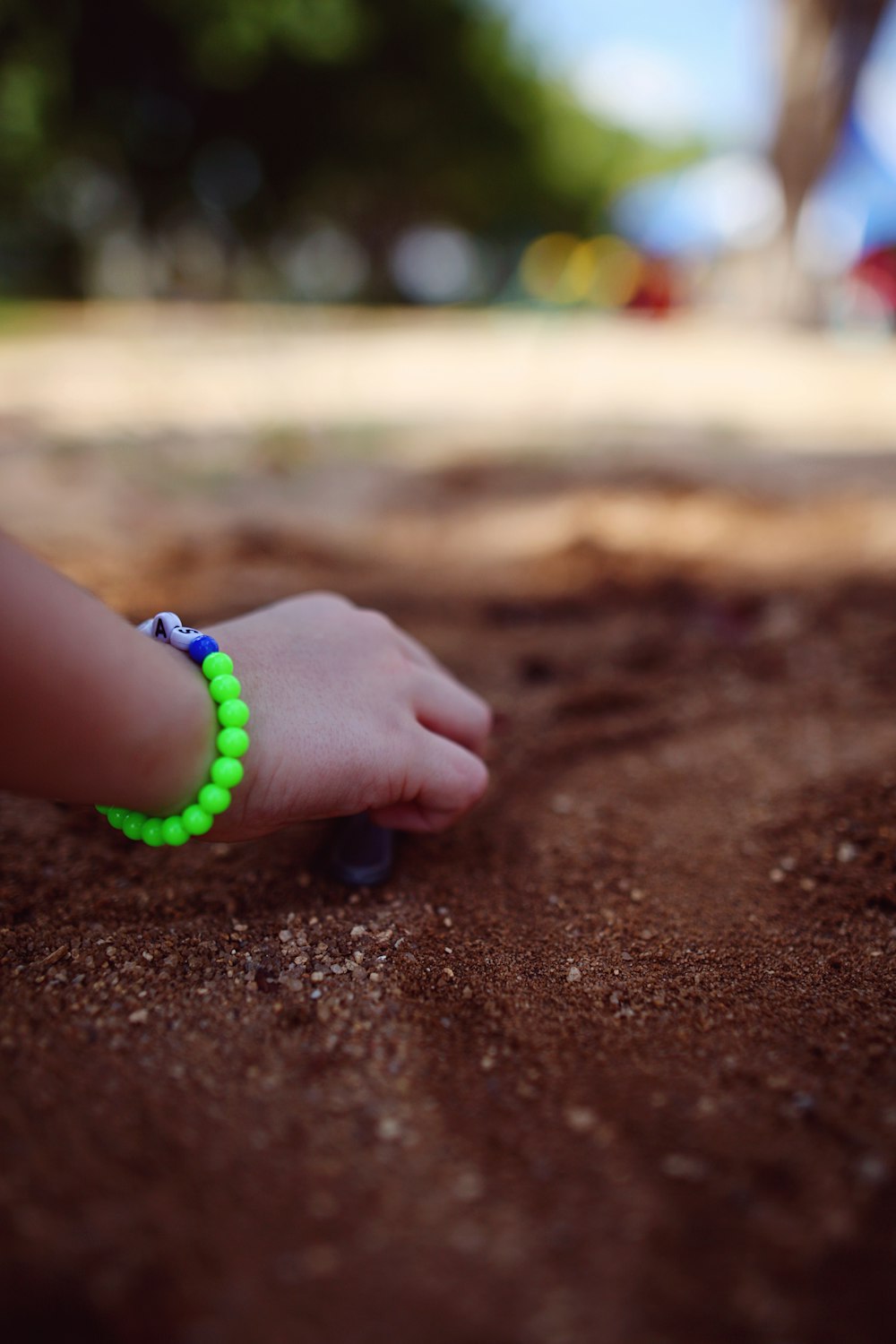 a child's hand with a green beaded bracelet