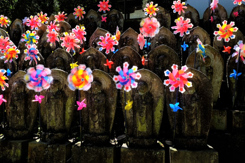 a bunch of fake flowers sitting on top of a wooden fence