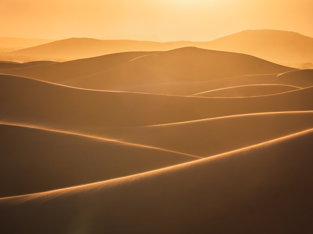 the sun is setting over the sand dunes