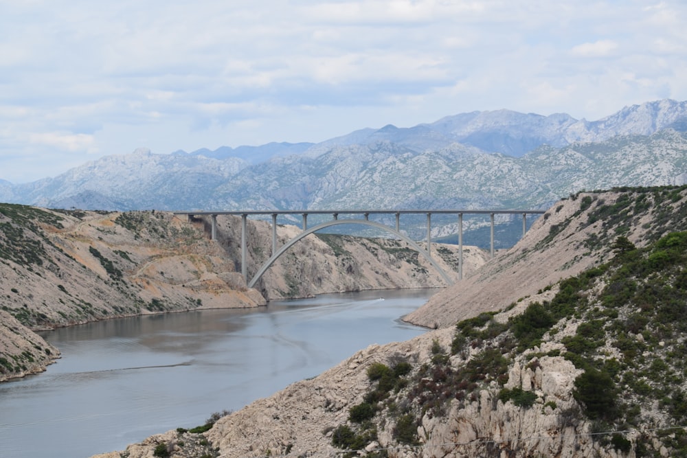 a bridge over a river with mountains in the background