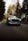 a silver car driving down a road with trees in the background