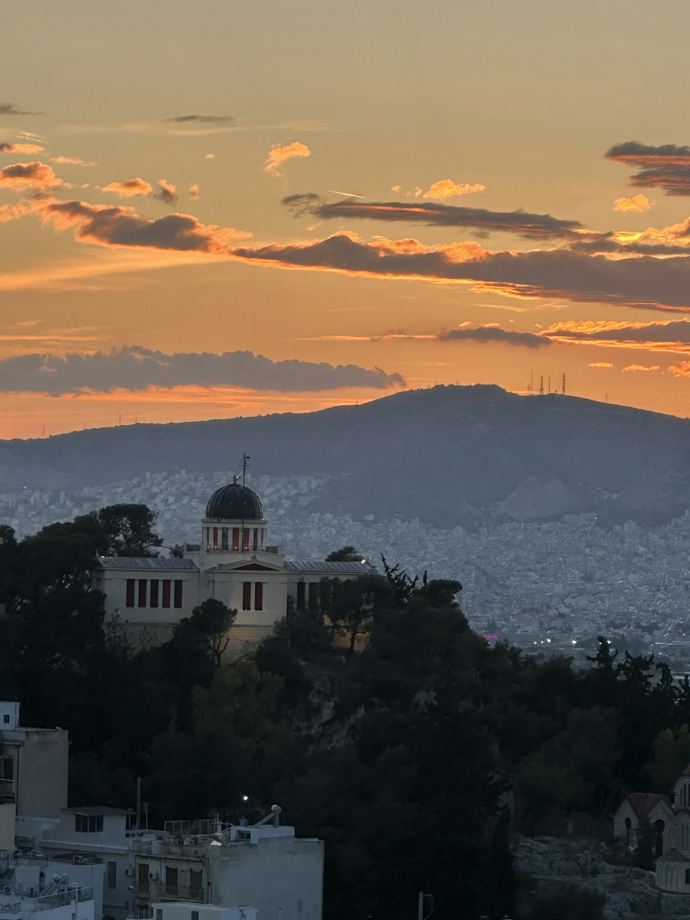 a sunset view of a city with mountains in the background