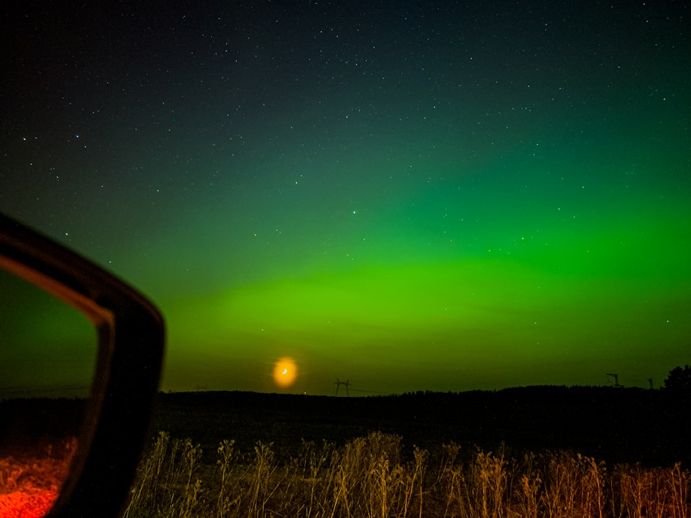 a green and red aurora over a field at night