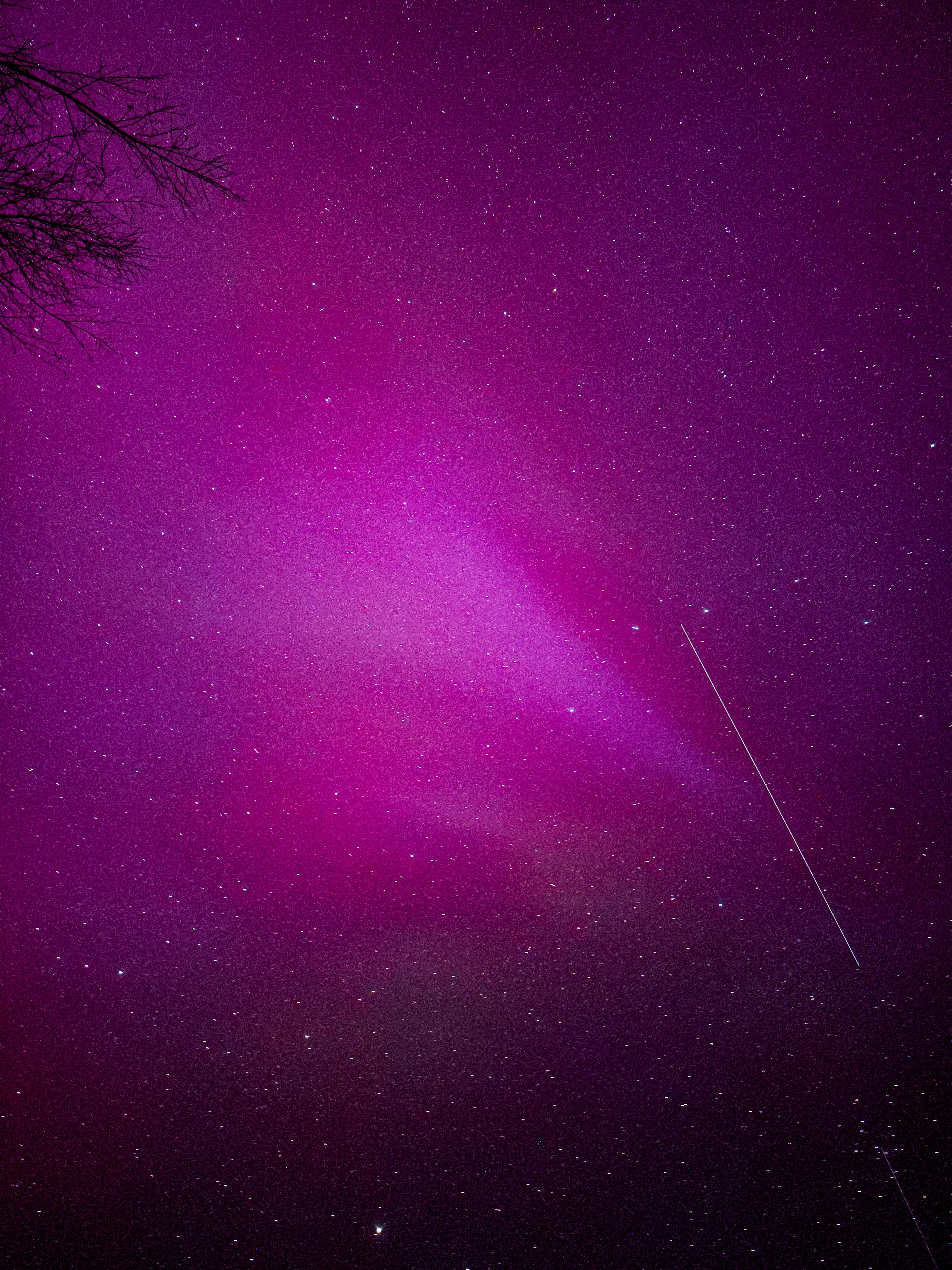 Un cielo púrpura con estrellas y un avión a lo lejos