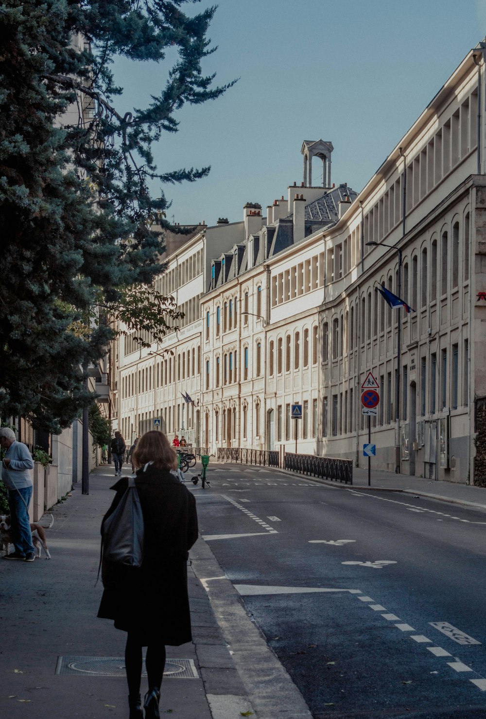 a woman walking down a street next to tall buildings