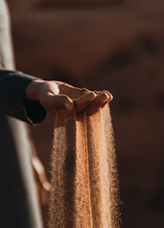 a person holding sand in their hands