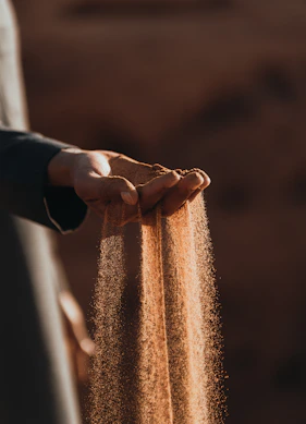 a person holding sand in their hands