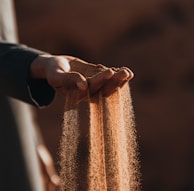 a person holding sand in their hands