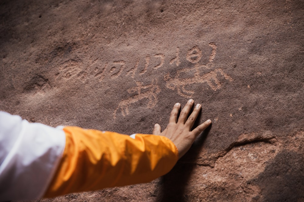 eine Person mit der Hand auf einem Felsen