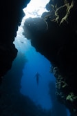 a person swimming in the water near a cave