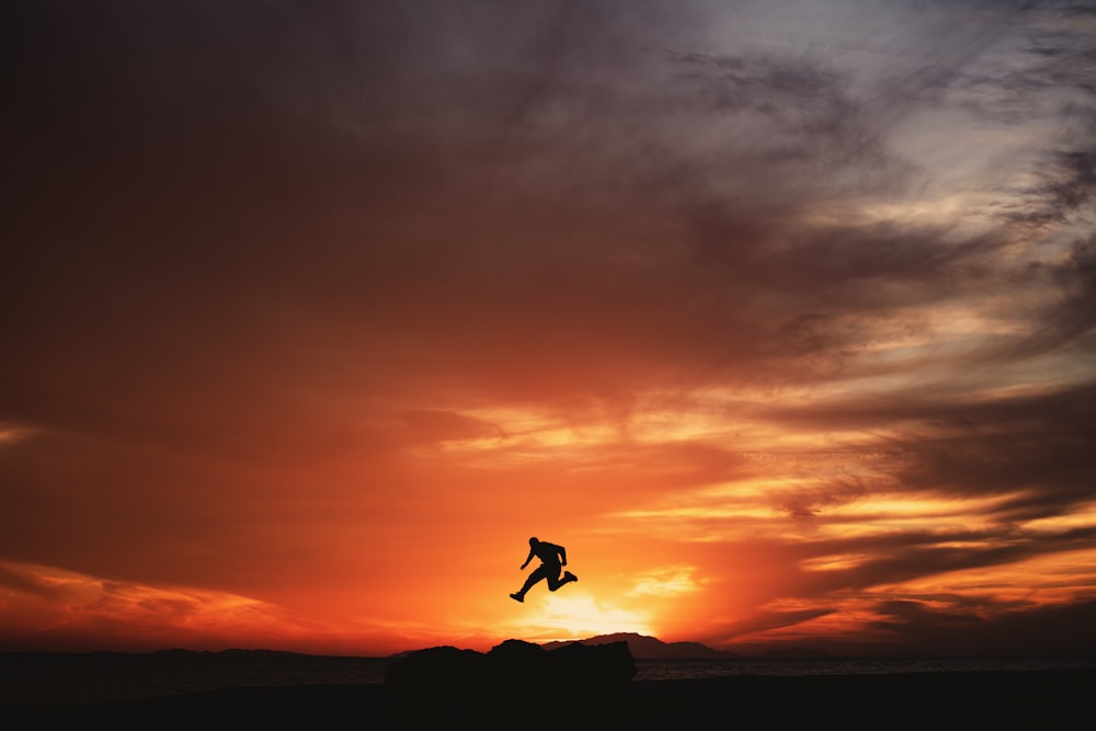 a person jumping into the air at sunset