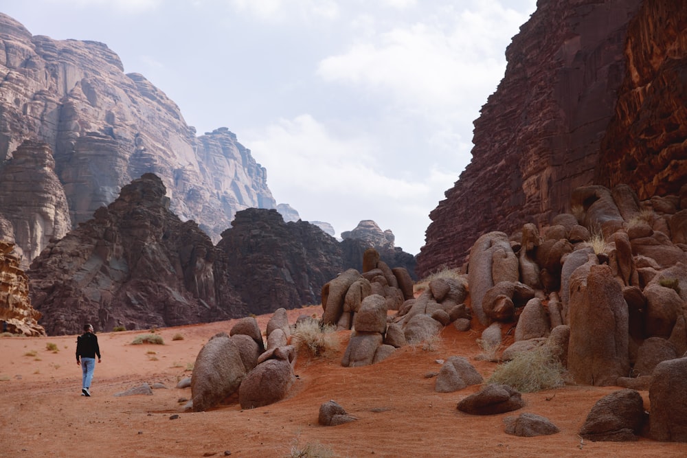 큰 바위가 있는 사막 지역을 걷는 사람