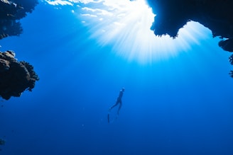 Underwater photo of a diver exploring a clear lake with sunlight filtering through the water