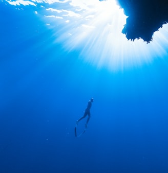 a person swimming in the ocean near a cave
