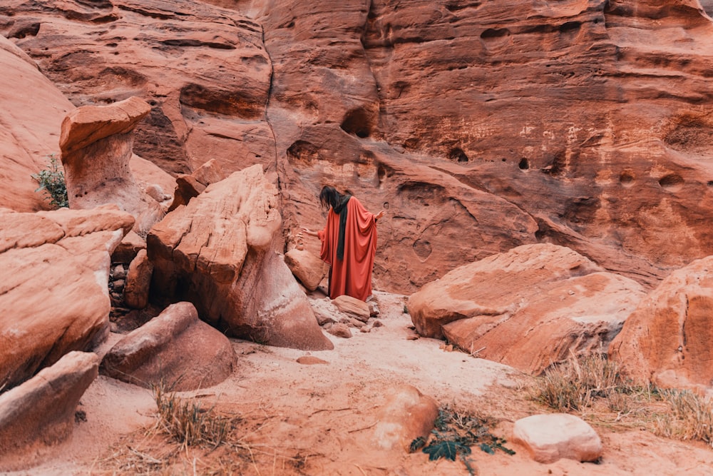 a woman in a red dress standing in a canyon