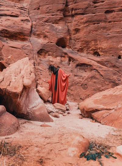 a woman in a red dress standing in a canyon