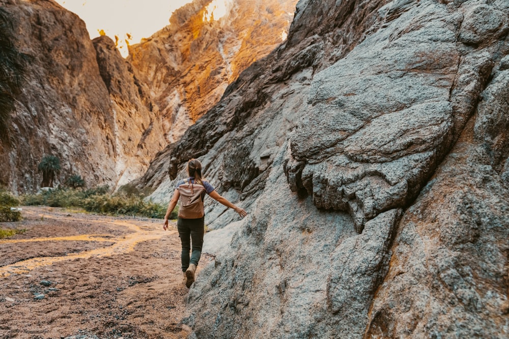 a woman climbing up a large rock in the mountains