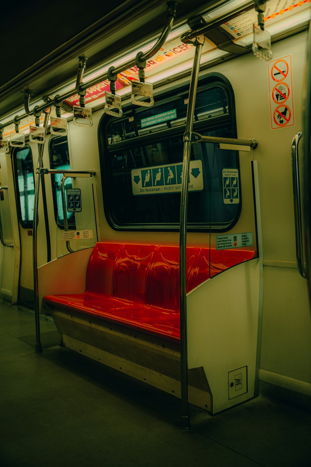 a red seat on a subway train next to a window