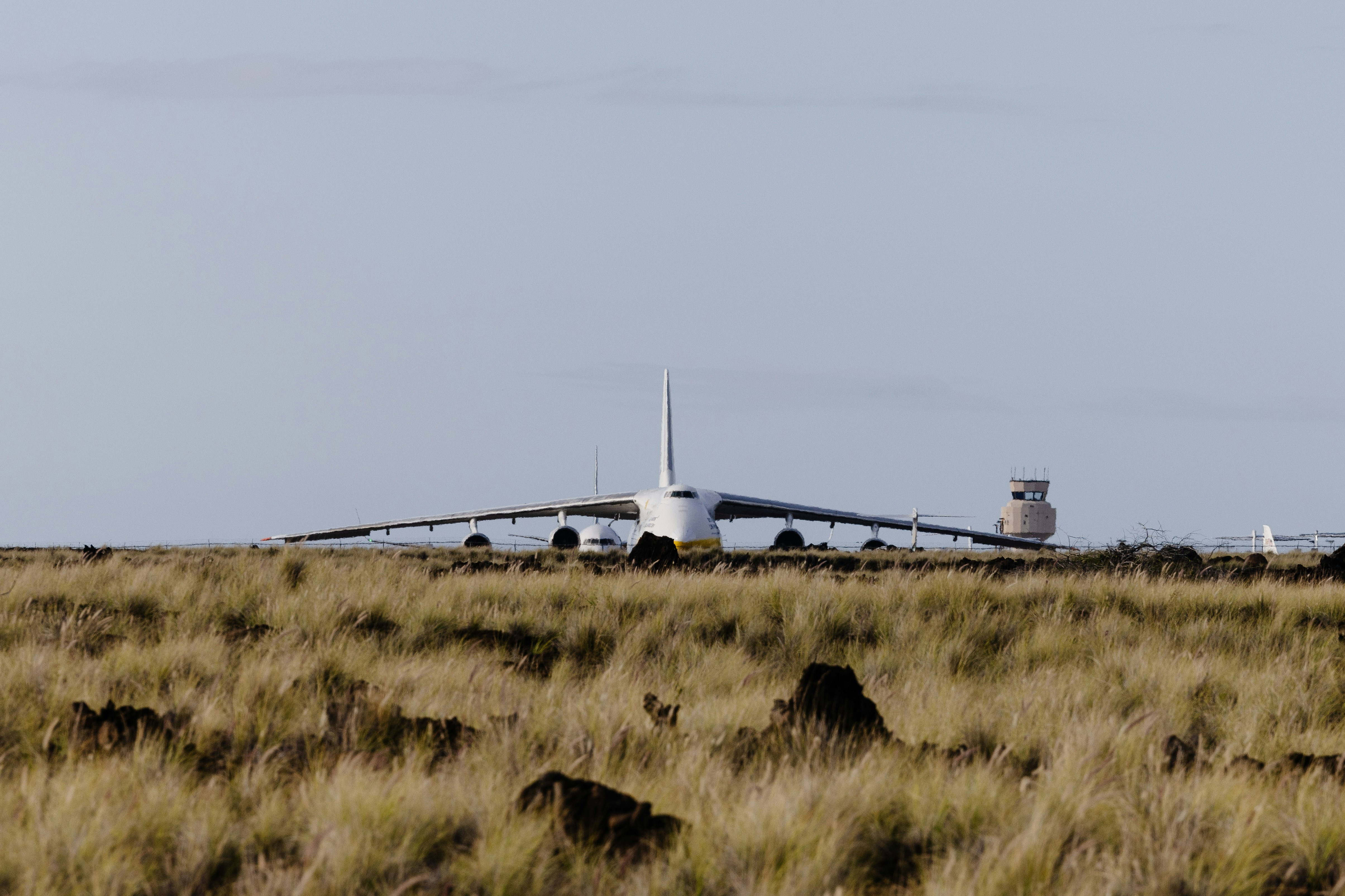 a large jetliner sitting on top of a dry grass field, 