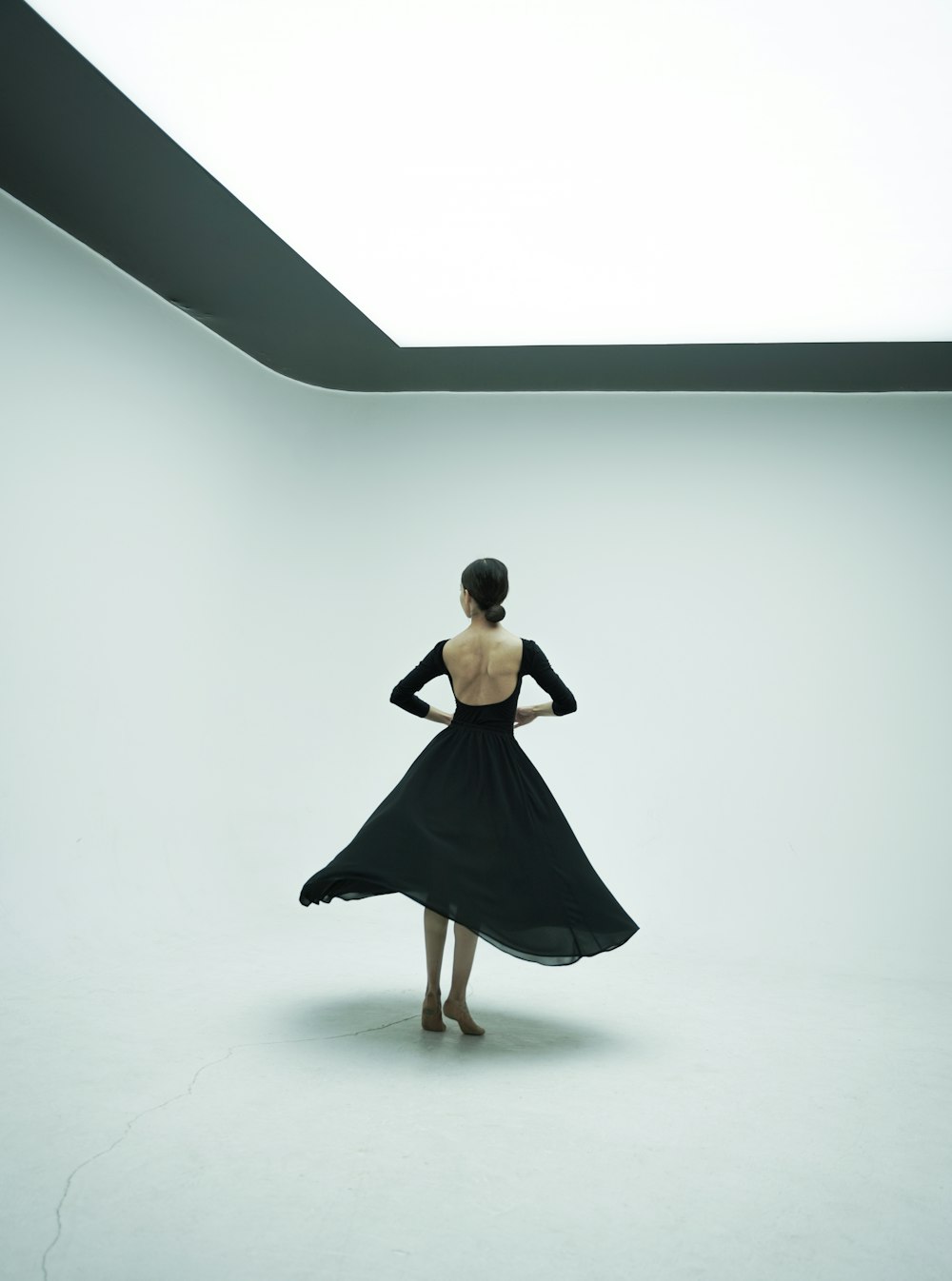 a woman in a black dress standing in a white room