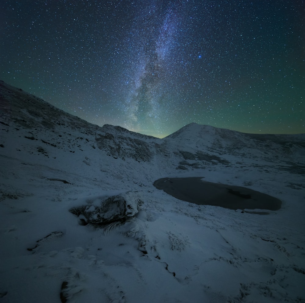 the night sky with stars above a snowy mountain