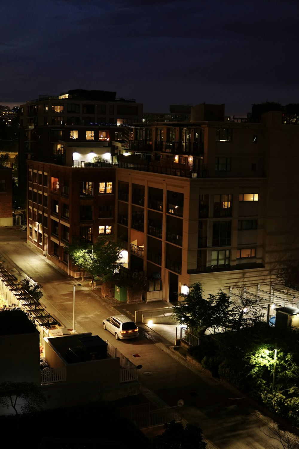 a city street at night with cars parked on the side of the road