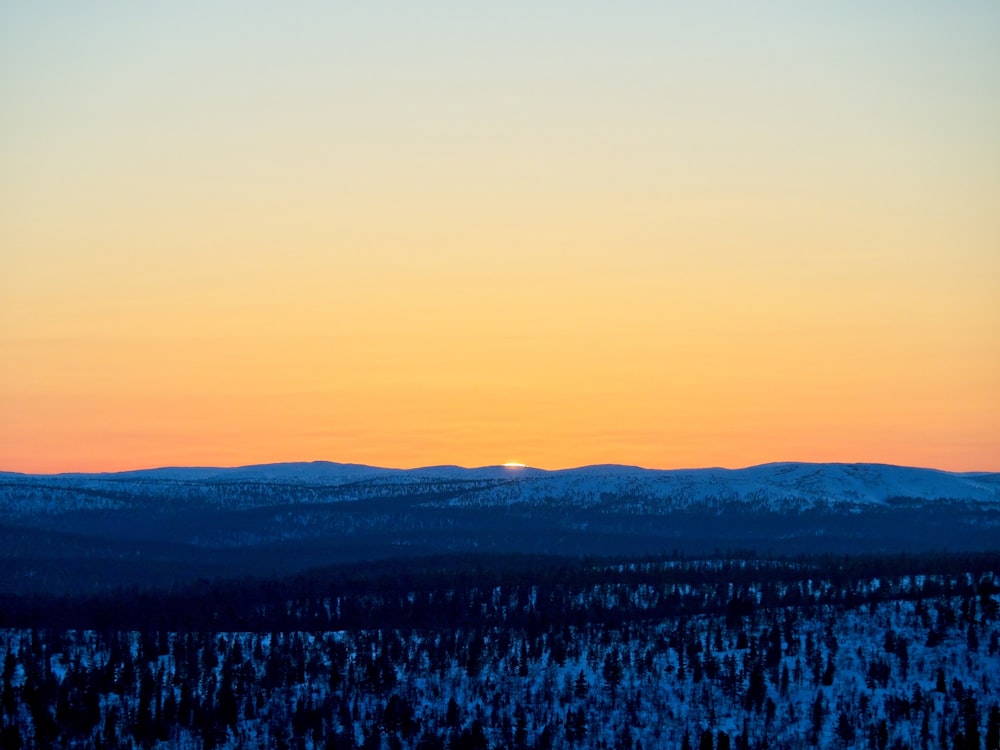 the sun is setting over the snowy mountains