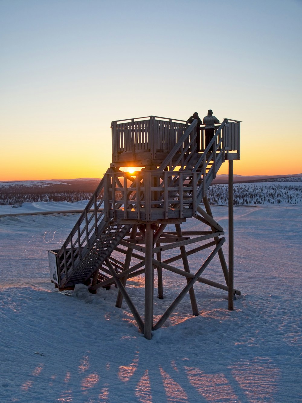 a lifeguard tower sitting in the middle of a snow covered field