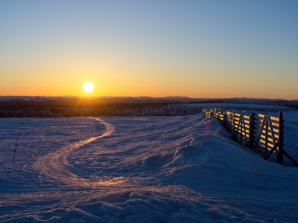 the sun is setting over a snowy field