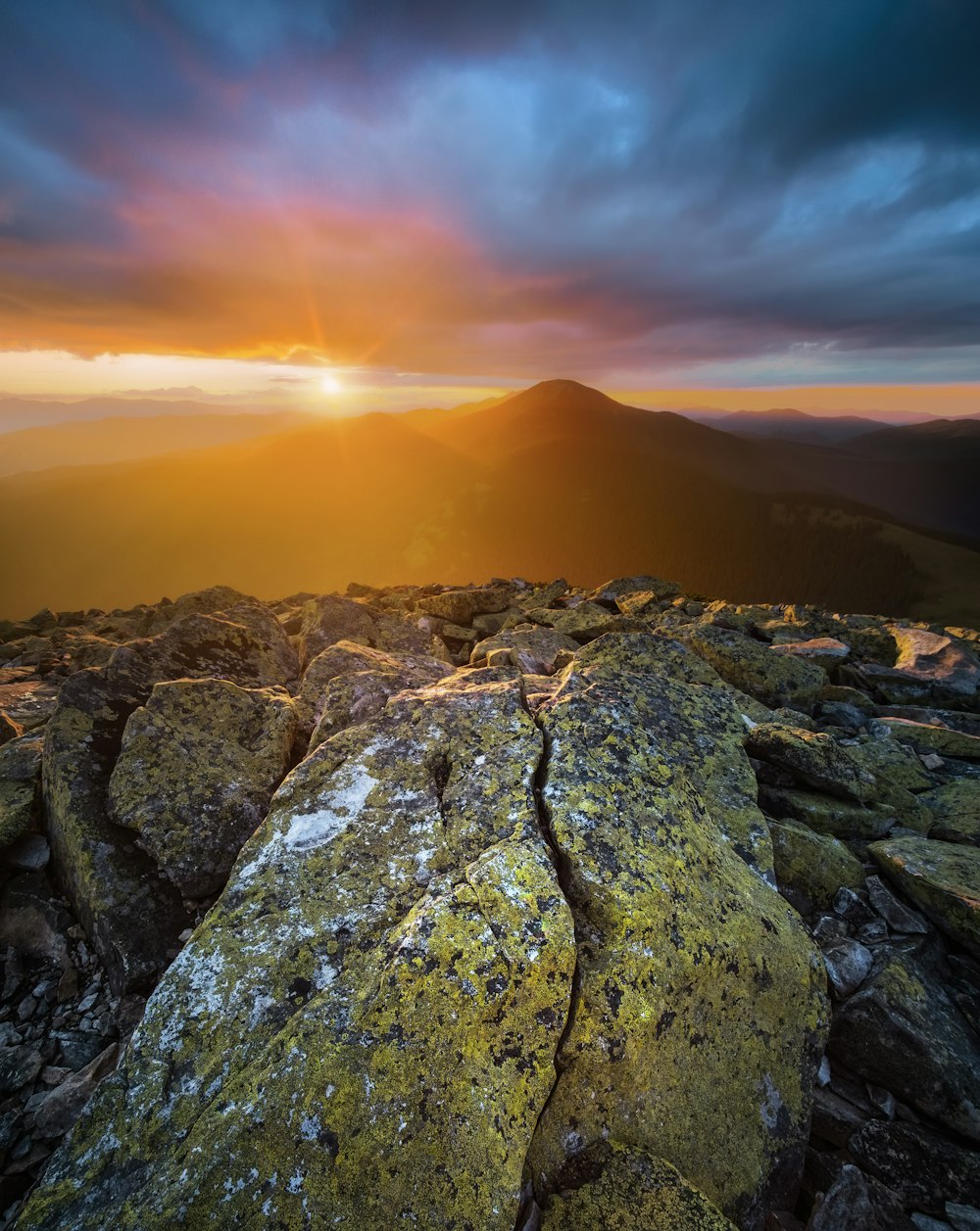 the sun is setting over a rocky mountain