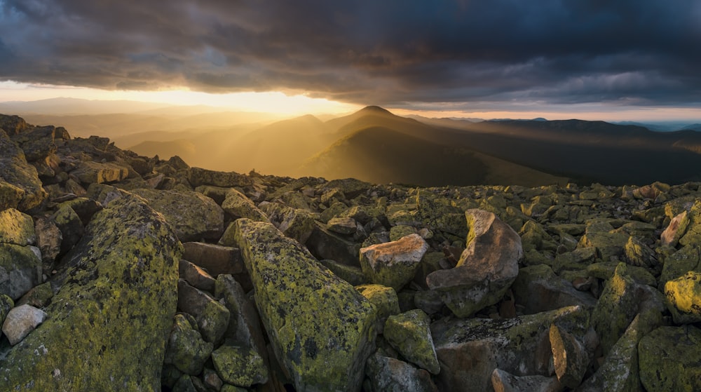 the sun shines through the clouds over a rocky terrain