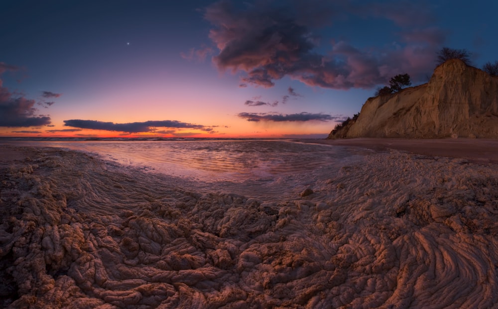 the sun is setting over the water at the beach