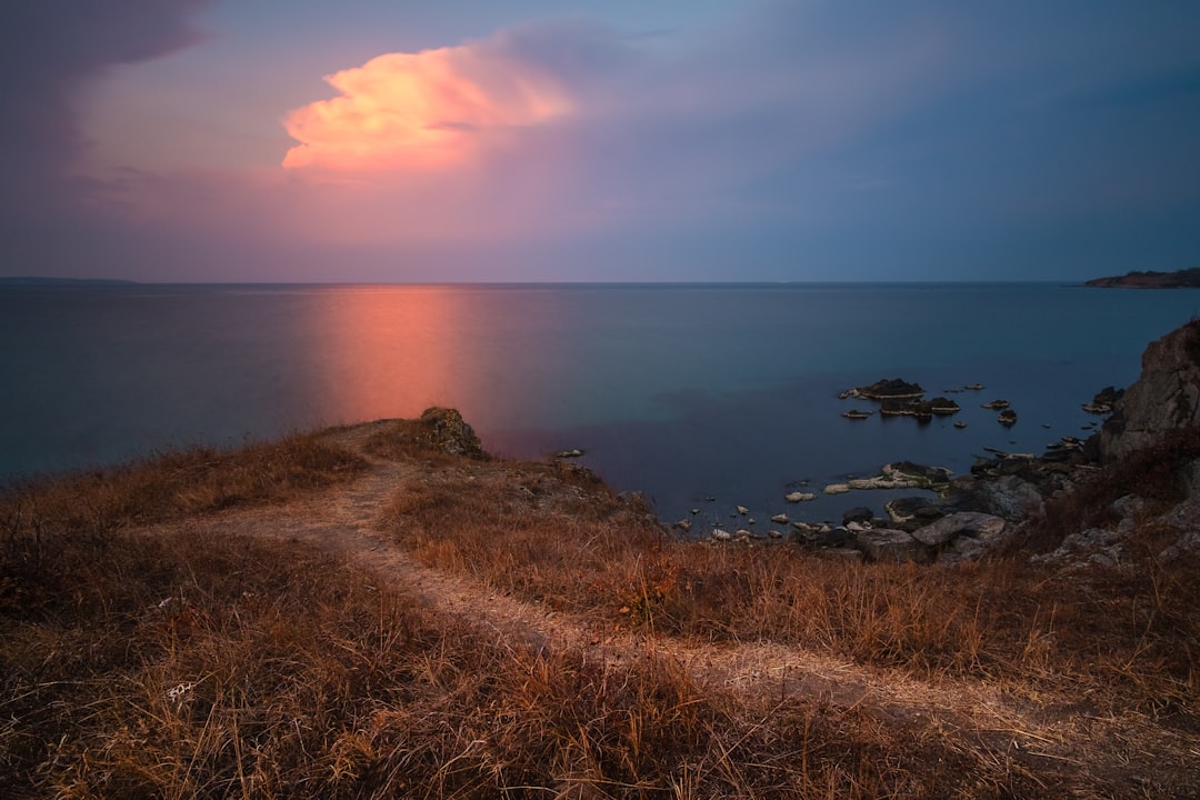 the sun is setting over a body of water, About a pink cloud