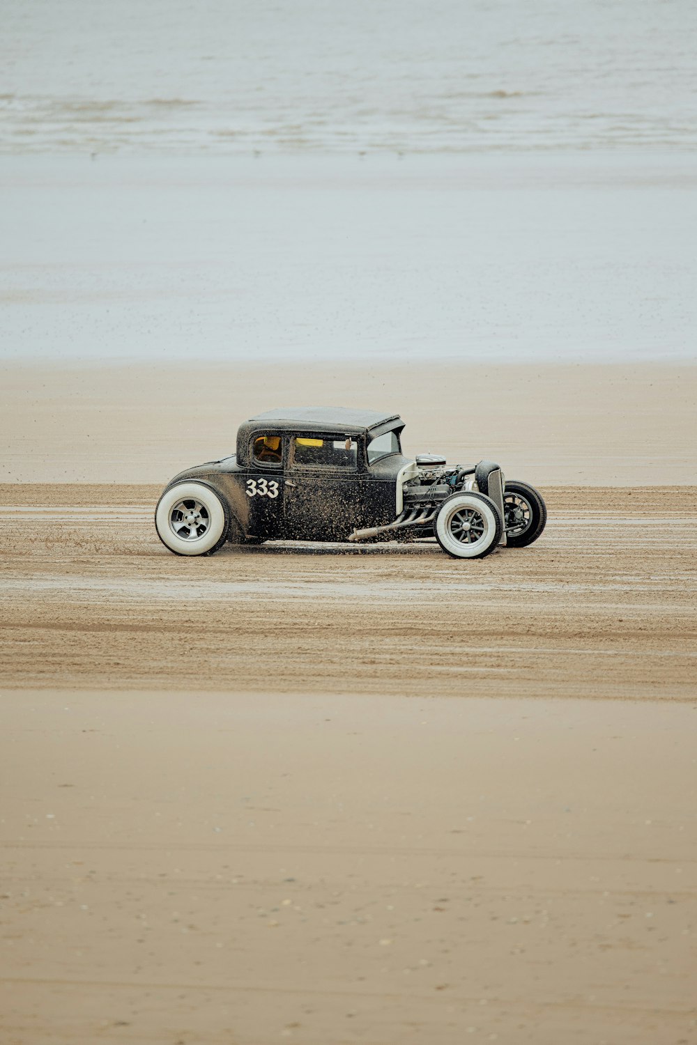 an old model t car driving on the beach