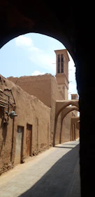 A narrow, sunlit alley in Nizwa lined with traditional Omani architecture.