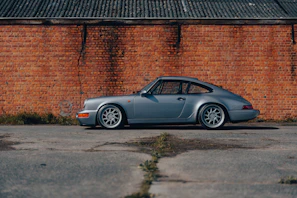 A classic vintage car restored to perfection, parked beside a rustic brick wall, evoking nostalgia.
