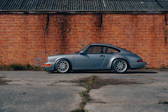 A classic vintage car restored to perfection, parked beside a rustic brick wall, evoking nostalgia.