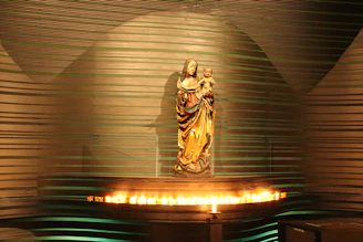 A delicate resin figure of a mother holding her child, glowing softly under warm light.