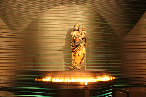 A delicate resin figure of a mother holding her child, glowing softly under warm light.